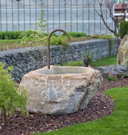 Handgefertigter Gartenbrunnen aus naturbelassenem Quarzit von Gasser Naturstein mit nostalgischem Messing-Wasserhahn im Garten. | © ©Gasser Naturstein