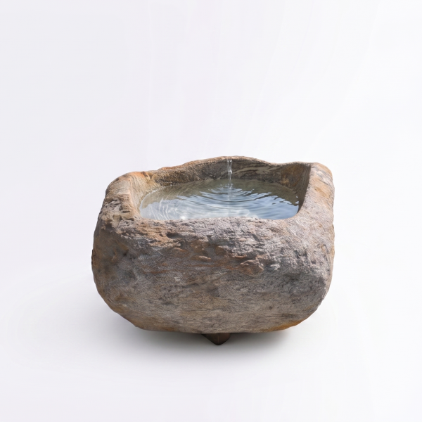 Natursteinbrunnen aus einem ausgehöhlten Granit-Findling als rustikale Wasserstelle im Garten