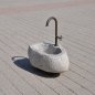 Natursteinbrunnen aus einem ausgehöhlten Granit-Findling als rustikale Wasserstelle im Garten