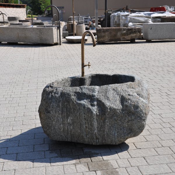 Handgearbeiteter Findlingsbrunnen aus massivem Naturstein mit natürlicher, rauer Felsstruktur
