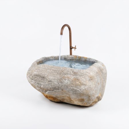 Natursteinbrunnen aus einem ausgehöhlten Granit-Findling als rustikale Wasserstelle im Garten