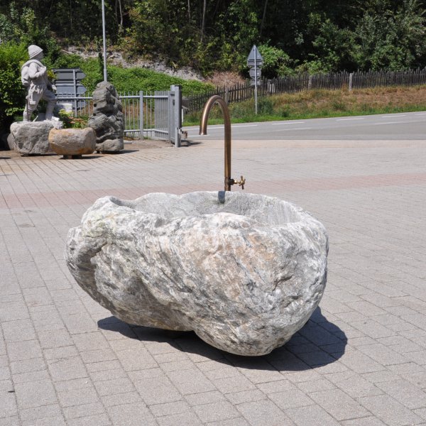 Handgearbeiteter Findlingsbrunnen aus massivem Naturstein mit natürlicher, rauer Felsstruktur