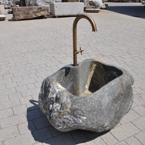 Natursteinbrunnen aus einem ausgehöhlten Granit-Findling als rustikale Wasserstelle im Garten