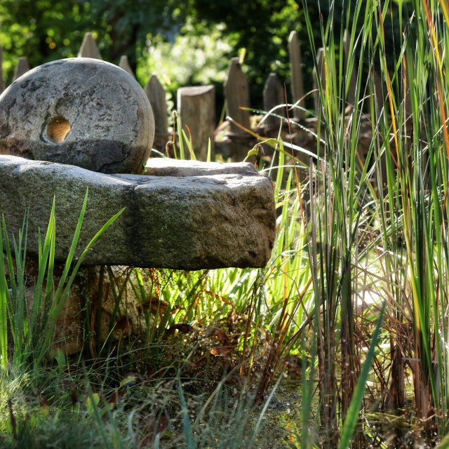 Als Gartendekoration am Teich: alte Getreidemühle aus Granit mit Mahlstein – Steinmetz-Handwerk aus Südtirol